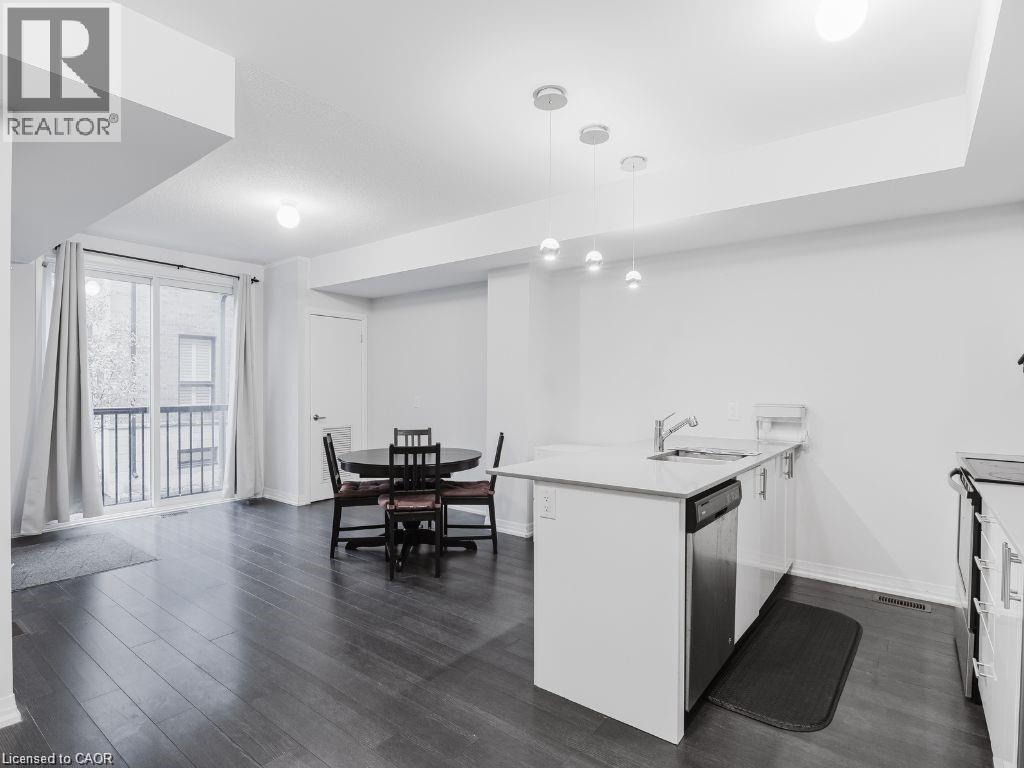 Kitchen featuring white cabinetry, a peninsula, dark wood finished floors, hanging light fixtures, and light stone countertops - 1206 Main Street E Unit# 113, Milton, ON - Indoor Photo Showing Other Room