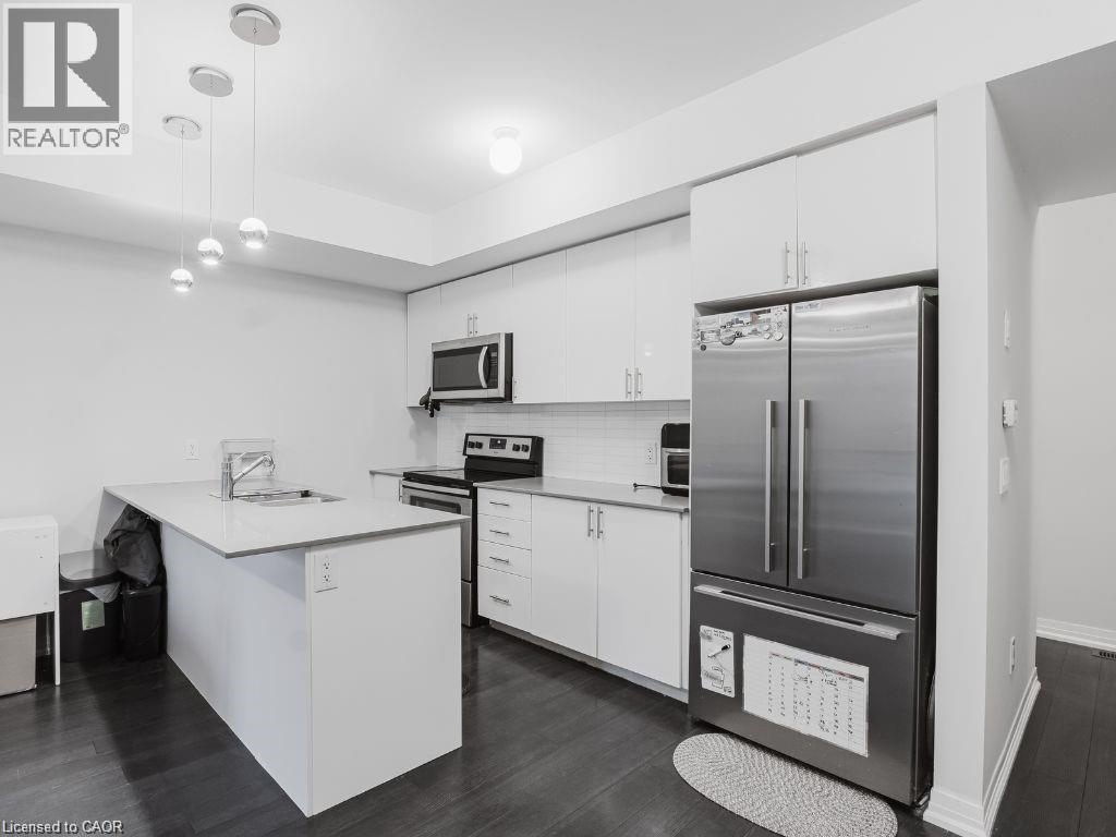 Kitchen with a peninsula, stainless steel appliances, white cabinets, and backsplash - 1206 Main Street E Unit# 113, Milton, ON - Indoor Photo Showing Kitchen