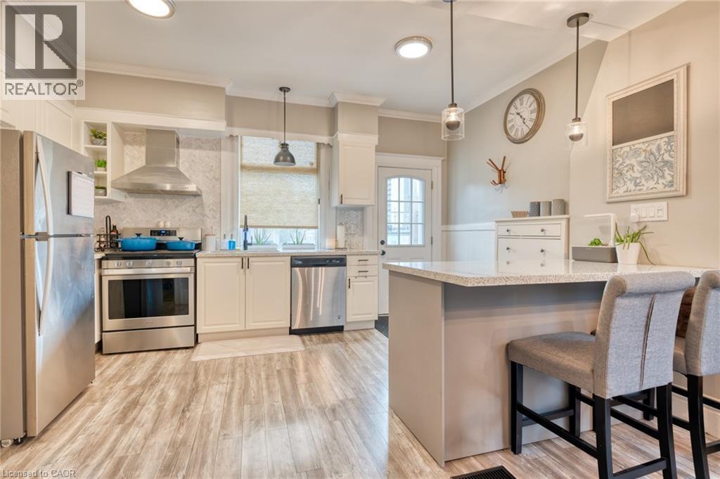 Kitchen featuring stainless steel appliances, a breakfast bar, light wood finished floors, a peninsula, and white cabinetry - 37 Cliff Avenue, Hamilton, ON - Indoor Photo Showing Kitchen With Upgraded Kitchen