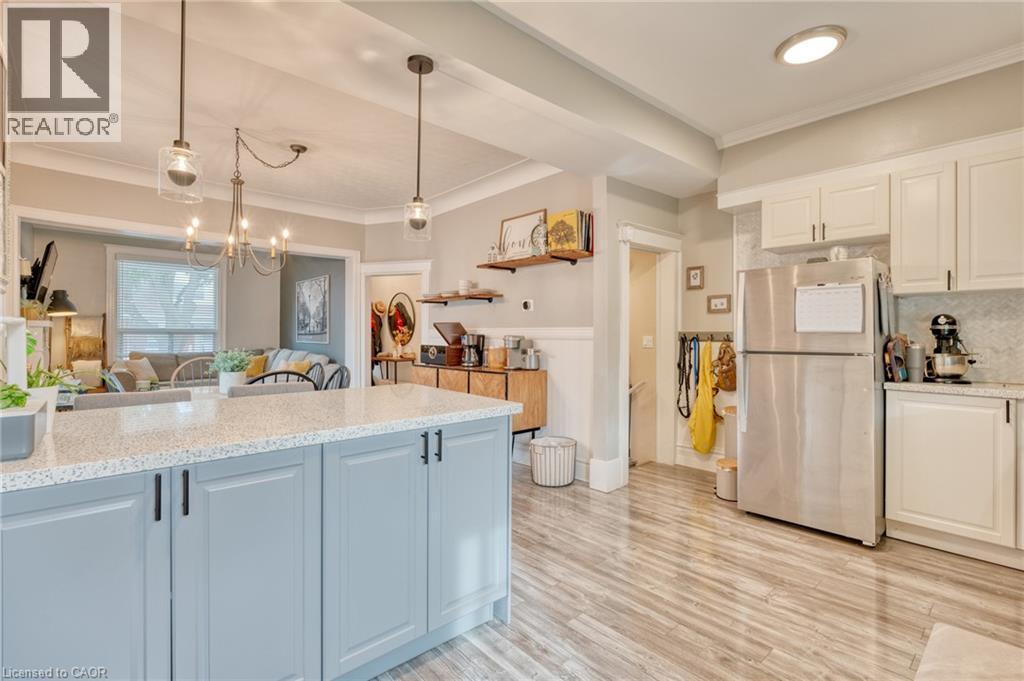 Kitchen with freestanding refrigerator, crown molding, light stone countertops, light wood-type flooring, and open floor plan - 37 Cliff Avenue, Hamilton, ON - Indoor Photo Showing Kitchen