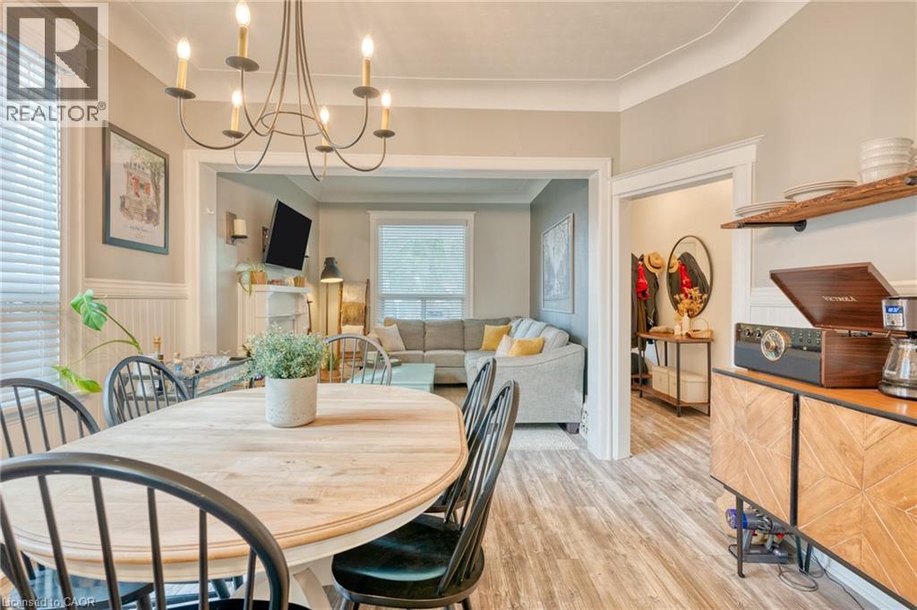 Dining area with a chandelier, light wood-style flooring, and wainscoting - 37 Cliff Avenue, Hamilton, ON - Indoor Photo Showing Dining Room