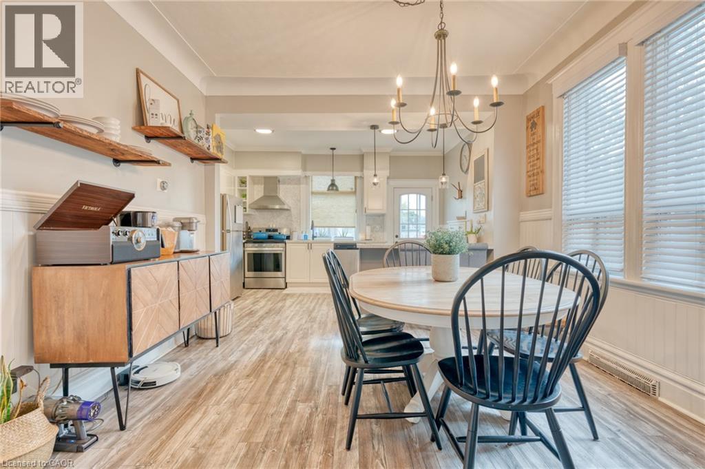 Dining space featuring wainscoting, hanging lights, light wood-style flooring, crown molding, and a decorative wall - 37 Cliff Avenue, Hamilton, ON - Indoor Photo Showing Dining Room