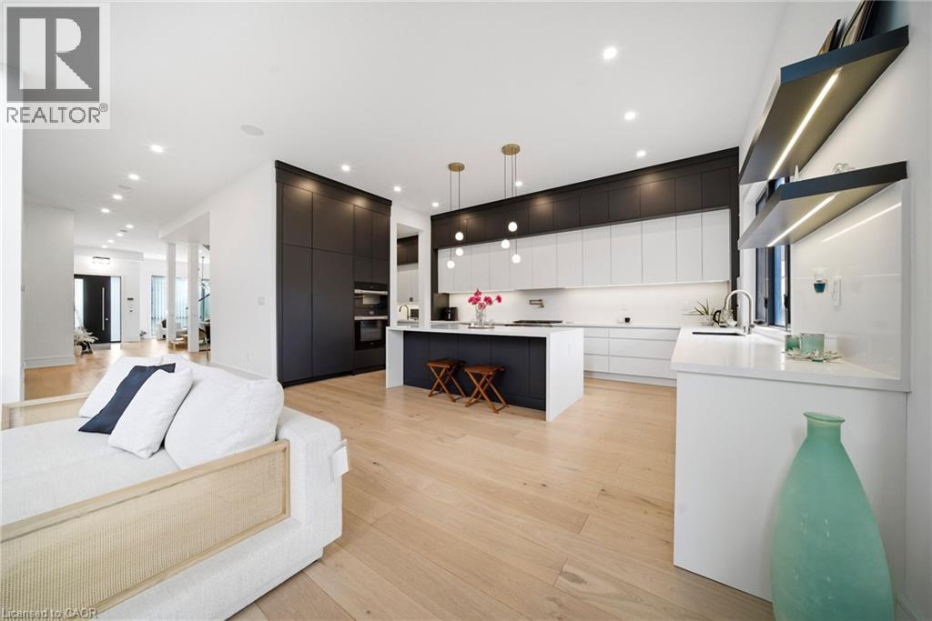 Dual tone kitchen featuring a kitchen breakfast bar, open floor plan, light wood-style flooring, modern cabinets, and a kitchen island - 2556 Glengarry Road, Mississauga, ON - Indoor