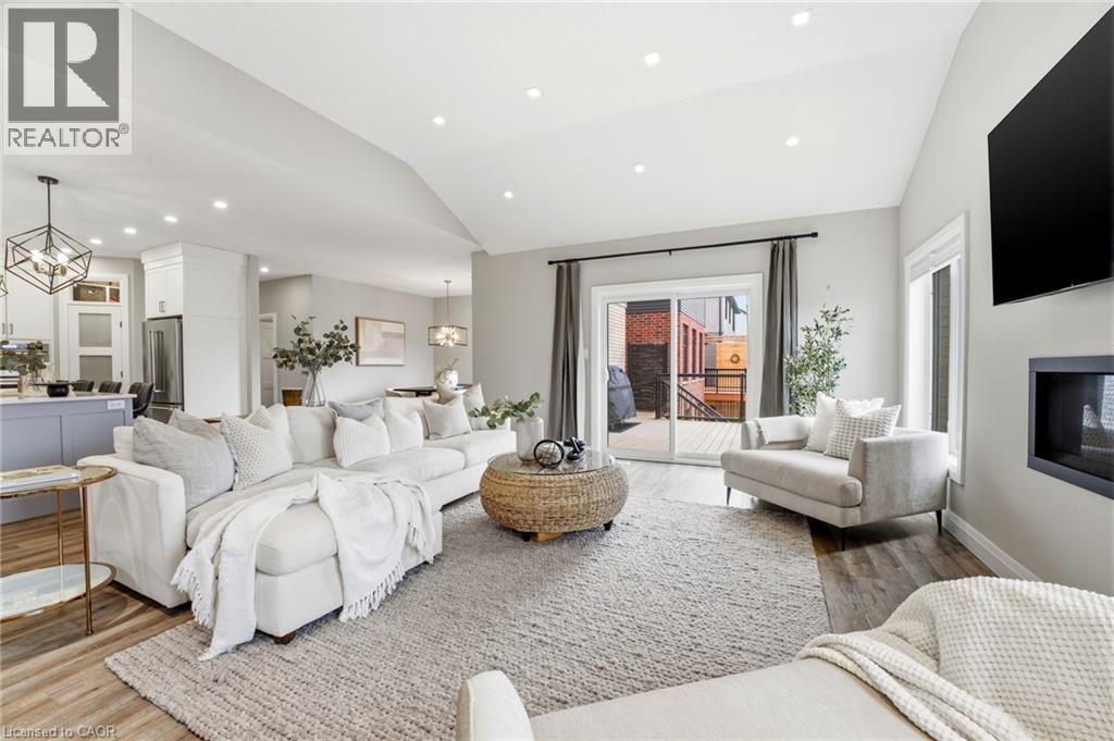 Living room featuring a chandelier, lofted ceiling, light wood-style flooring, and a glass covered fireplace - 39 Mill Race Crescent, St. Jacobs, ON - Indoor Photo Showing Living Room With Fireplace