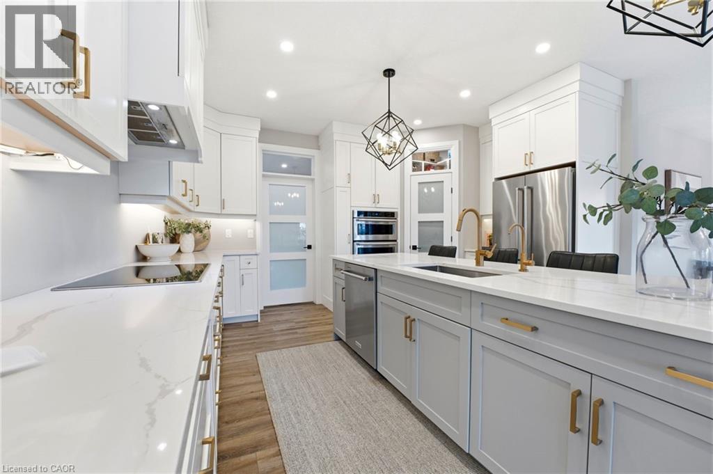 Kitchen with light stone countertops, hanging lights, light wood-type flooring, stainless steel appliances, and dual tone cabinetry - 39 Mill Race Crescent, St. Jacobs, ON - Indoor Photo Showing Kitchen With Upgraded Kitchen