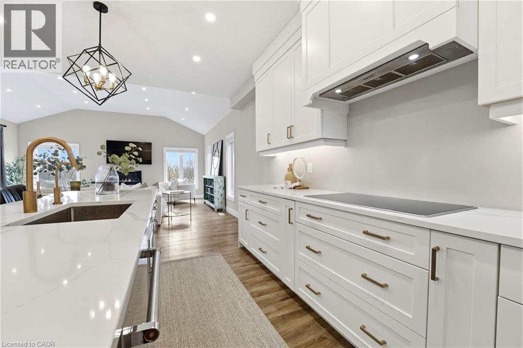 Kitchen featuring white cabinetry, vaulted ceiling, dark wood-style floors, light stone countertops, and hanging lights - 39 Mill Race Crescent, St. Jacobs, ON - Indoor Photo Showing Kitchen With Upgraded Kitchen