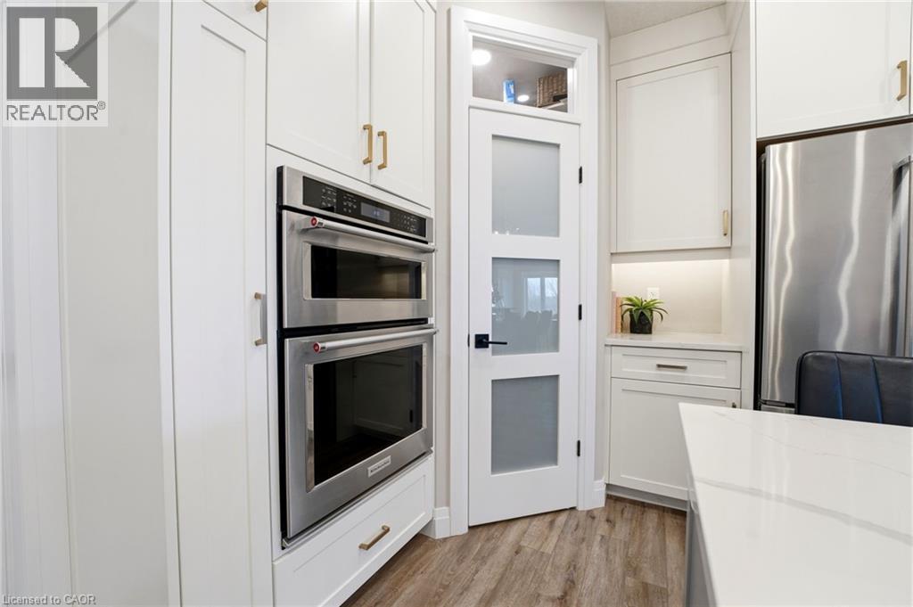 Kitchen featuring stainless steel appliances, white cabinets, light wood finished floors, and light stone counters - 39 Mill Race Crescent, St. Jacobs, ON - Indoor Photo Showing Kitchen