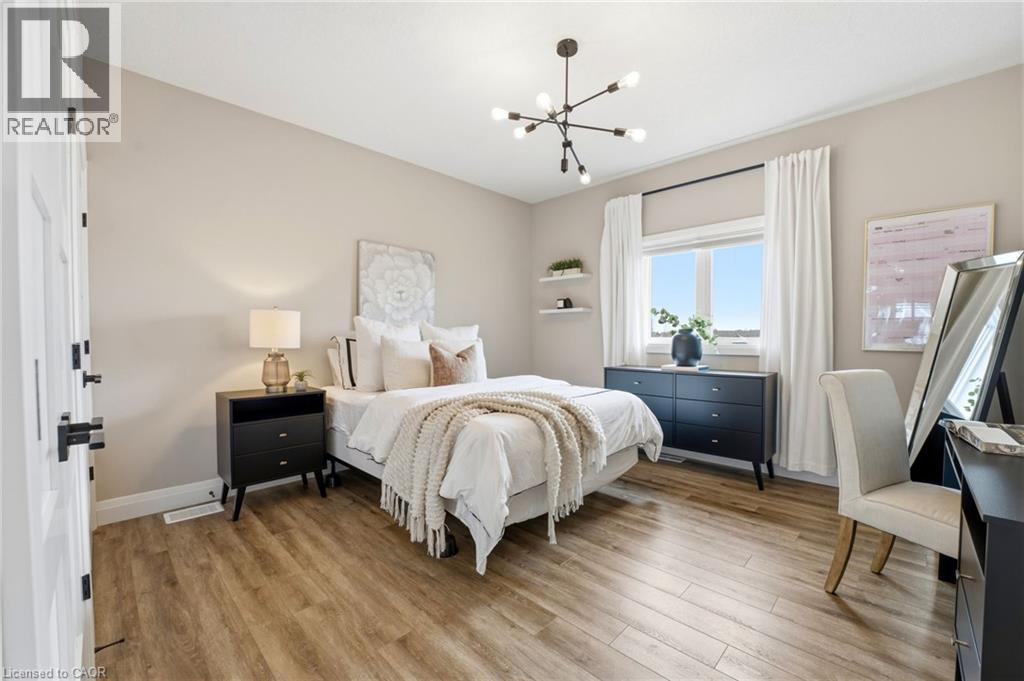 Bedroom with light wood finished floors and suspended lighting - 39 Mill Race Crescent, St. Jacobs, ON - Indoor Photo Showing Bedroom
