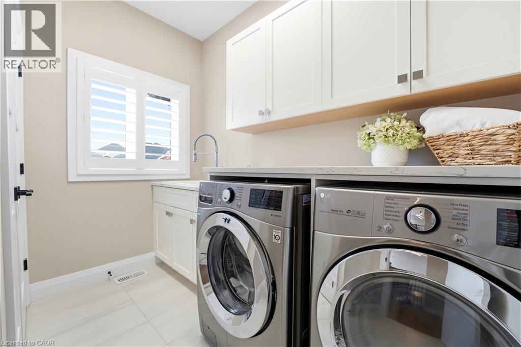 Laundry area with cabinet space, light tile patterned floors, and washer and dryer - 39 Mill Race Crescent, St. Jacobs, ON - Indoor Photo Showing Laundry Room