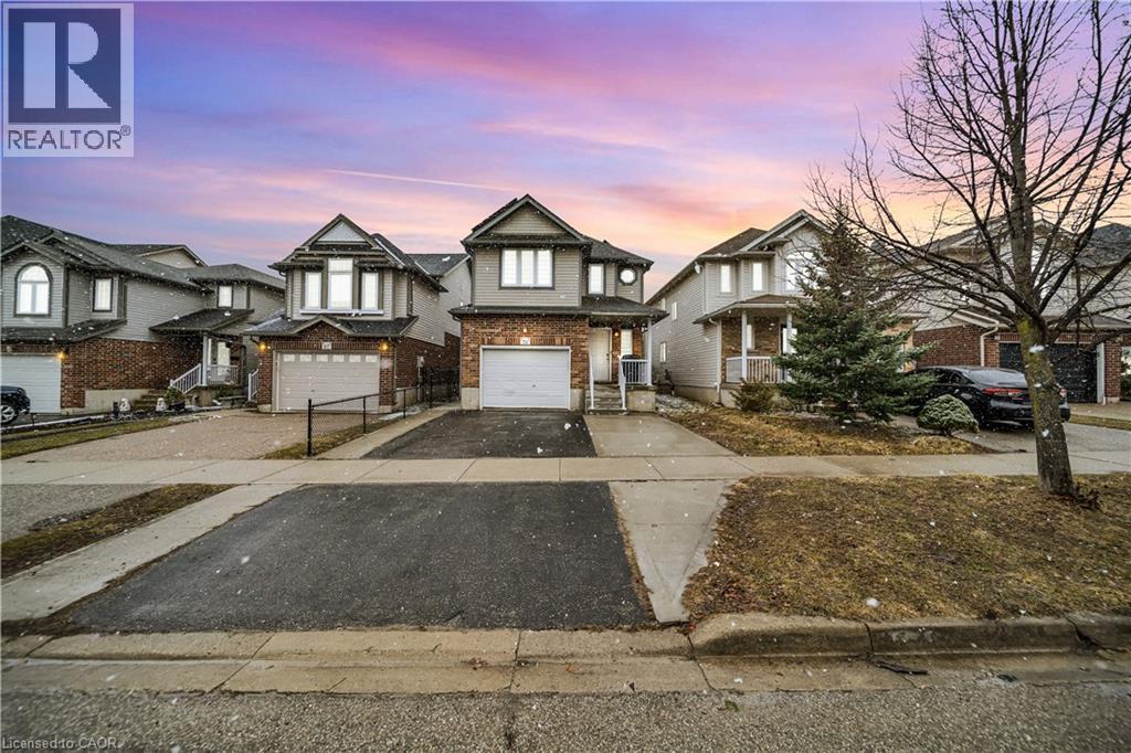 View of front of house with asphalt driveway, a garage, brick siding, and a residential view - 51 Seabrook Drive, Kitchener, ON - Outdoor With Facade