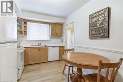 Kitchen with white appliances, light countertops, glass insert cabinets, light wood-type flooring, and wood finish cabinets -