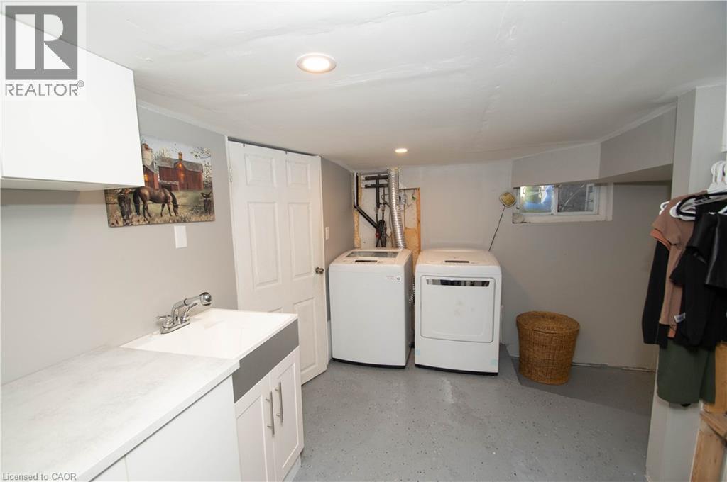 Laundry room featuring finished concrete flooring, washing machine and clothes dryer, cabinet space, and recessed lighting - 535 Mcdowell Road E, Simcoe, ON