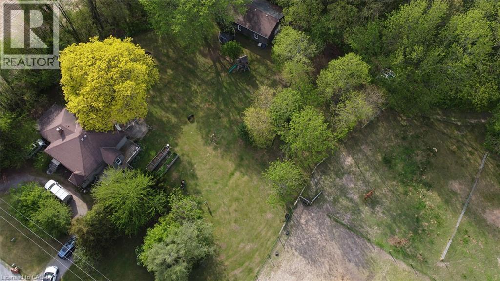 Expansive property featuring a brown roofline, abundant mature trees, a substantial green space, and a dedicated driveway - 535 Mcdowell Road E, Simcoe, ON