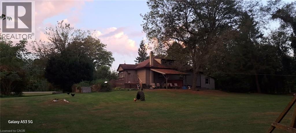 View of green lawn featuring view of wooded area and a wooden deck - 535 Mcdowell Road E, Simcoe, ON