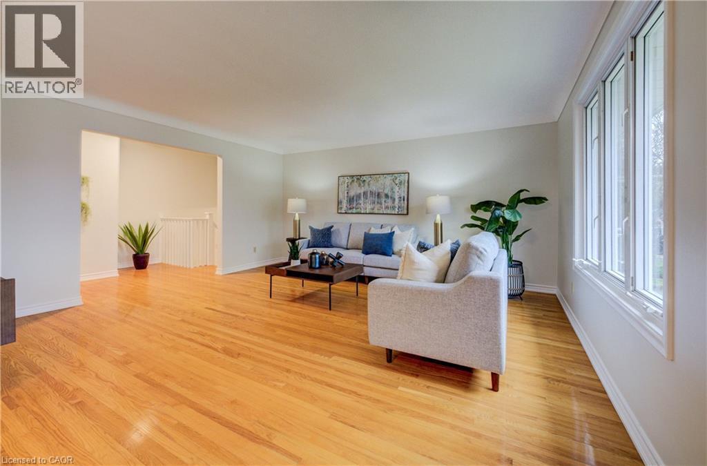 Main floor living room with gleaming, original hardwood flooring, bright windows and open to dining room - 66 Tupper Crescent, Kitchener, ON - Indoor Photo Showing Living Room
