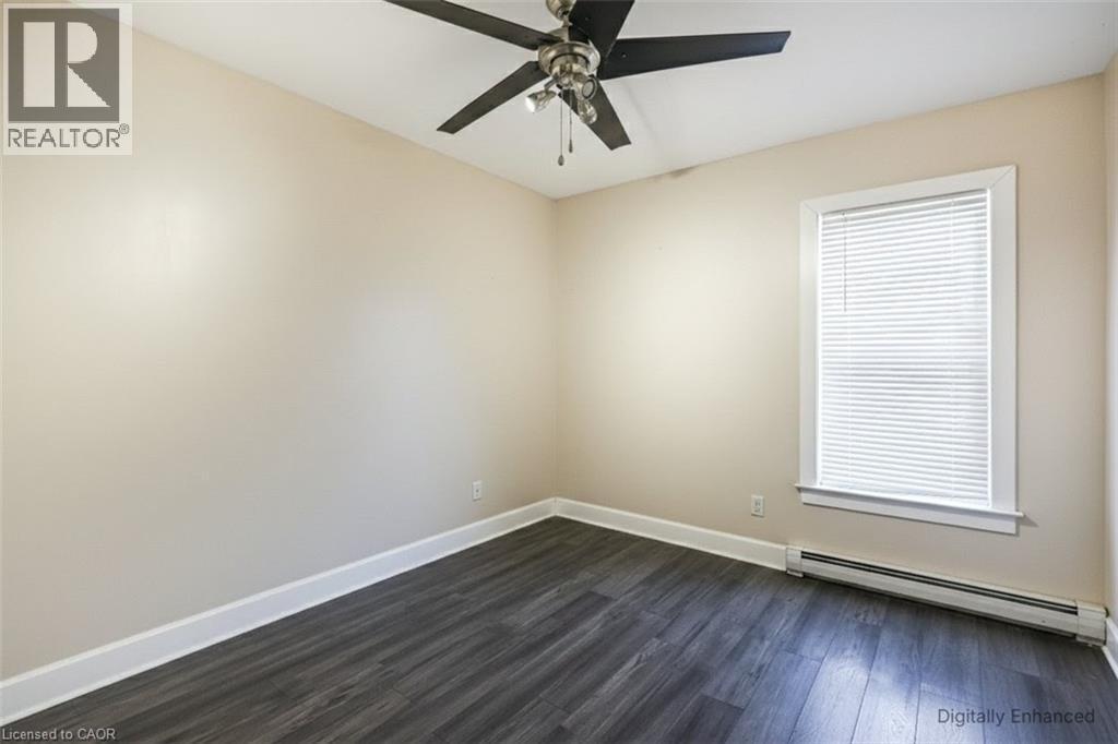 Spare room with a baseboard radiator, dark wood-style floors, ceiling fan, and plenty of natural light - 27 Ashley Street, Hamilton, ON - Indoor Photo Showing Other Room