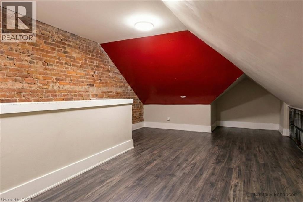 Additional living space with dark wood-type flooring, brick wall, and lofted ceiling - 27 Ashley Street, Hamilton, ON - Indoor Photo Showing Other Room