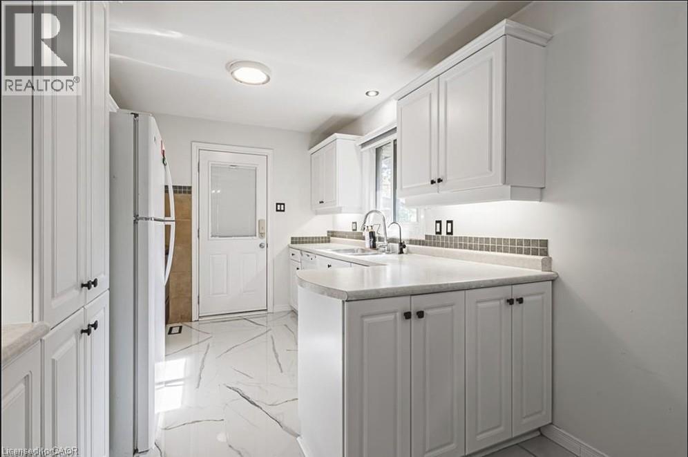 Kitchen with white cabinets, light countertops, freestanding refrigerator, light marble finish floors, and a peninsula - 267 Erb Street E, Waterloo, ON - Indoor