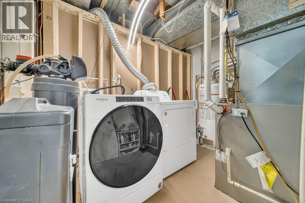 Laundry area with heating unit, finished concrete floors, washing machine and dryer, and gas water heater - 267 Erb Street E, Waterloo, ON - Indoor Photo Showing Laundry Room