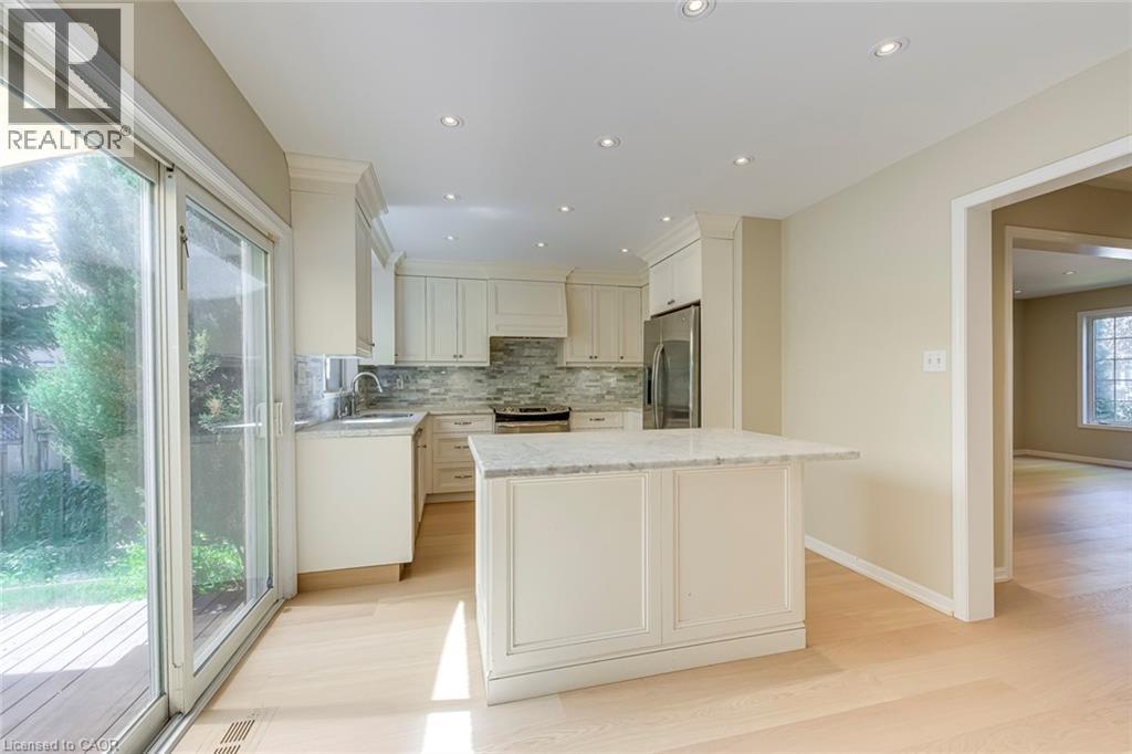 Kitchen featuring light stone counters, tasteful backsplash, stainless steel appliances, light wood-style flooring, and recessed lighting - 3037 Abernathy Way, Oakville, ON - Indoor Photo Showing Kitchen With Upgraded Kitchen