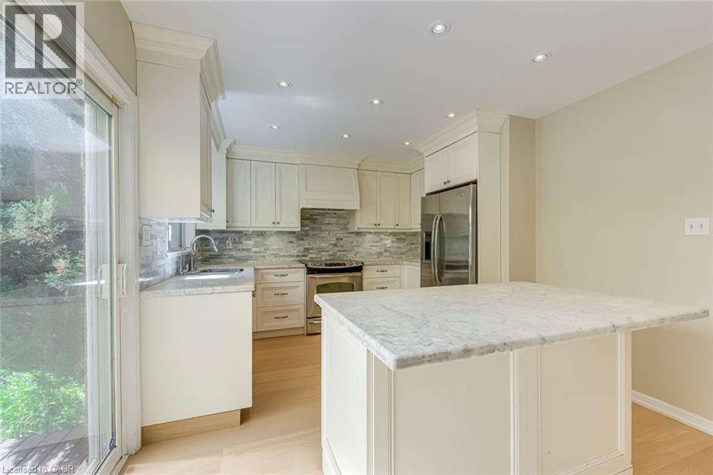 Kitchen with stainless steel appliances, light stone counters, white cabinets, tasteful backsplash, and recessed lighting - 3037 Abernathy Way, Oakville, ON - Indoor Photo Showing Kitchen With Upgraded Kitchen