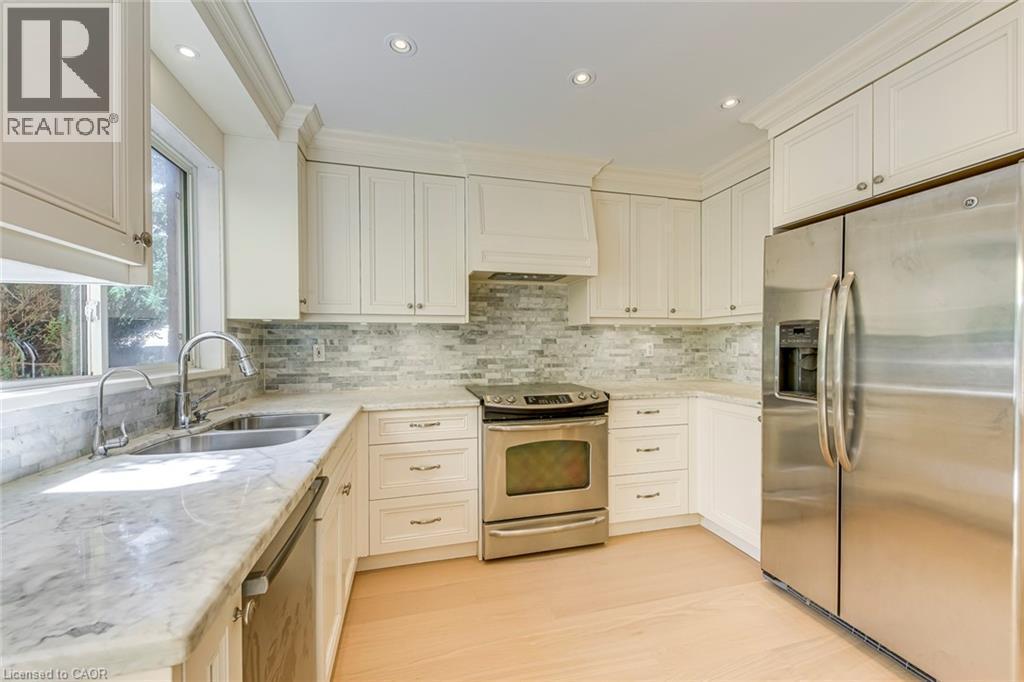 Kitchen featuring stainless steel appliances, light stone counters, recessed lighting, tasteful backsplash, and white cabinets - 3037 Abernathy Way, Oakville, ON - Indoor Photo Showing Kitchen With Double Sink With Upgraded Kitchen