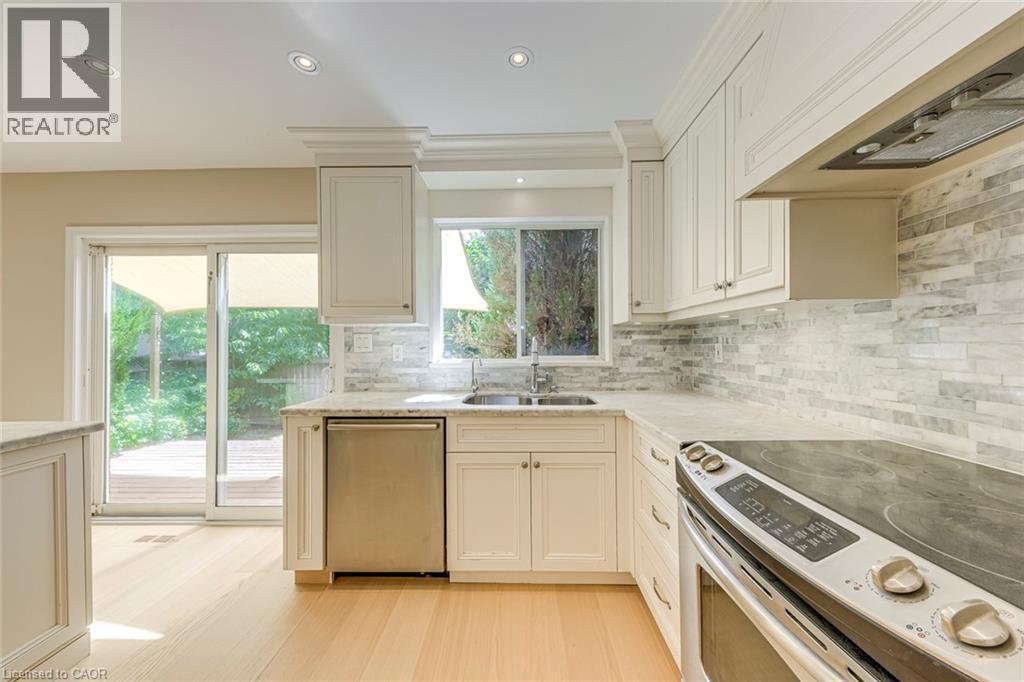 Kitchen with stainless steel appliances, recessed lighting, light stone counters, tasteful backsplash, and light wood finished floors - 3037 Abernathy Way, Oakville, ON - Indoor Photo Showing Kitchen With Double Sink With Upgraded Kitchen