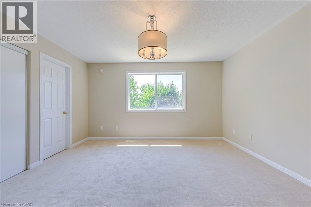 Primary bedroom featuring light carpet, a textured ceiling, and a closet - 3037 Abernathy Way, Oakville, ON - Indoor Photo Showing Other Room