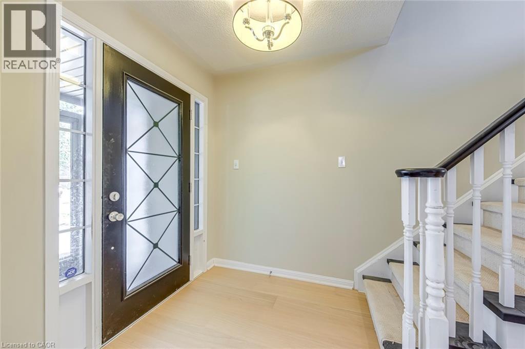 Foyer entrance featuring light wood-style flooring, healthy amount of natural light, and a textured ceiling - 3037 Abernathy Way, Oakville, ON - Indoor Photo Showing Other Room