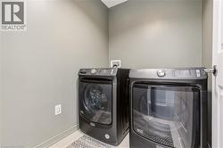 Laundry area with washing machine and clothes dryer and light tile patterned flooring -