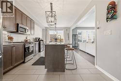 Kitchen with stainless steel appliances, a center island with sink, light stone counters, dark wood finish cabinets, and a kitchen bar -