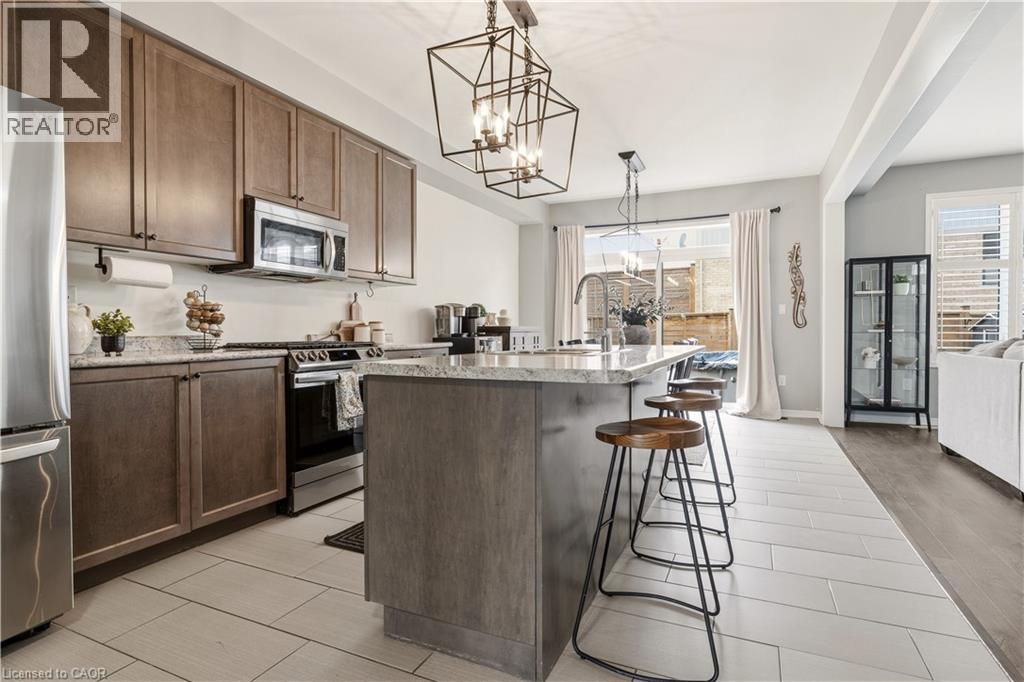Kitchen with a kitchen island with sink, stainless steel appliances, a kitchen bar, suspended lighting, and wood tiled floors - 105 Larry Crescent, Caledonia, ON - Indoor Photo Showing Kitchen With Stainless Steel Kitchen With Upgraded Kitchen