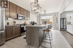 Kitchen with a kitchen island with sink, stainless steel appliances, a kitchen bar, suspended lighting, and wood tiled floors -