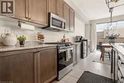 Kitchen with stainless steel appliances, wine cooler, decorative light fixtures, and light stone countertops -