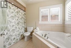 Bathroom with a bath, a shower with shower curtain, and light tile patterned floors -