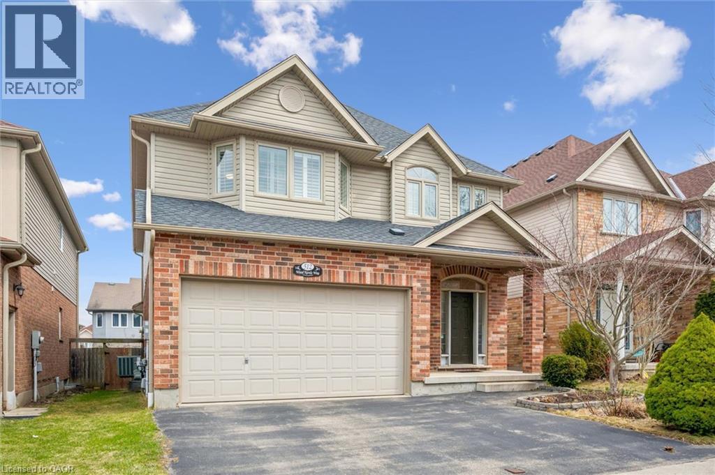 View of front of house with asphalt driveway, an attached garage, a shingled roof, and brick siding - 512 Wood Nettle Way, Waterloo, ON - Outdoor With Facade