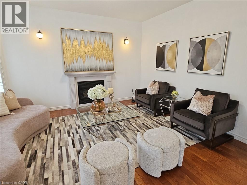 Living area featuring hardwood flooring, a fireplace with a detailed mantelpiece, and neutral wall tones - 512 Wood Nettle Way, Waterloo, ON - Indoor Photo Showing Living Room With Fireplace