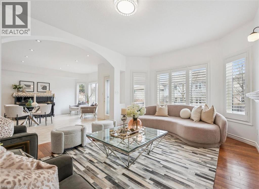 Bright living area featuring a bay window with plantation shutters, recessed lighting, and wood-finish flooring - 512 Wood Nettle Way, Waterloo, ON - Indoor Photo Showing Living Room