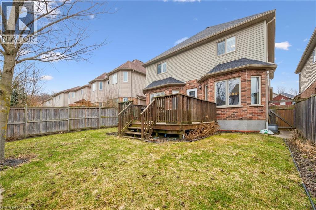 Back of property with a fenced backyard, a wooden deck, brick siding, a gate, and a residential view - 512 Wood Nettle Way, Waterloo, ON - Outdoor