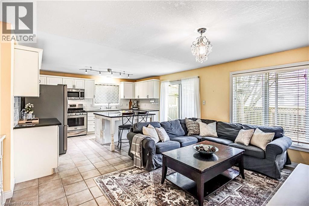 Living room featuring light tile patterned flooring, hanging lights, and a textured ceiling - 65 Thistlemoor Drive, Caledonia, ON - Indoor Photo Showing Living Room