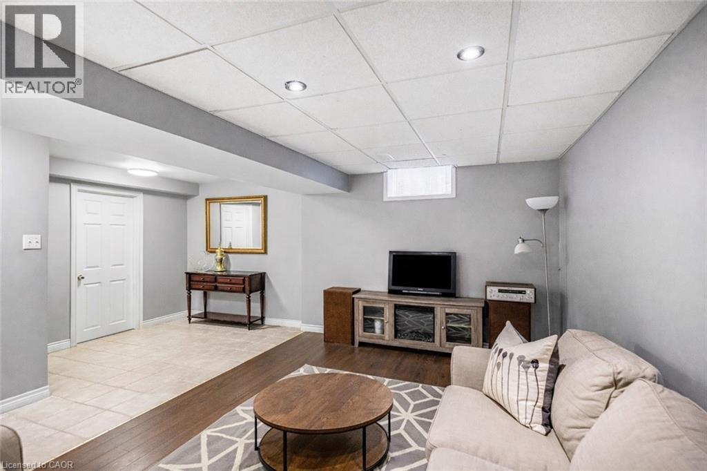 Living area with a paneled ceiling and wood finished floors - 65 Thistlemoor Drive, Caledonia, ON - Indoor Photo Showing Basement