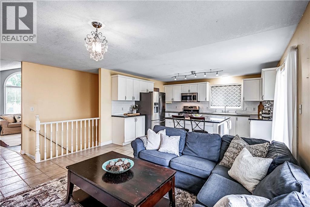 Living room with a textured ceiling, suspended lighting, and light tile patterned flooring - 65 Thistlemoor Drive, Caledonia, ON - Indoor Photo Showing Living Room