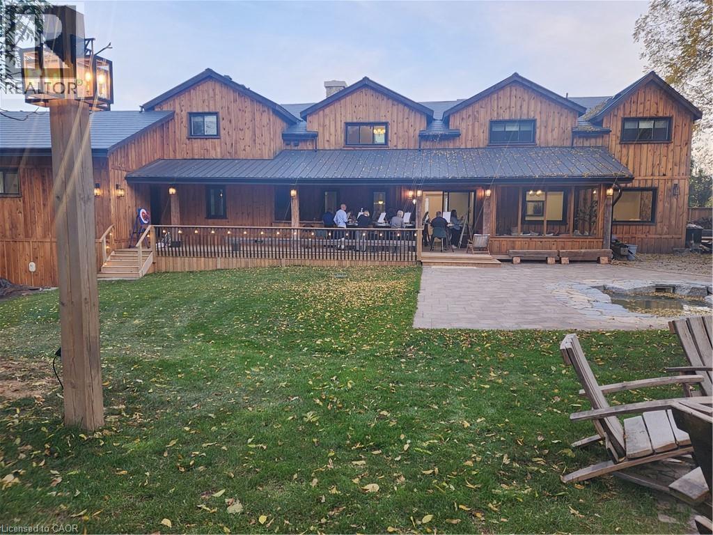 Back of house with a lawn, an outdoor fire pit, a metal roof, board and batten siding, and a patio area - 2019 Dundas Street, Burlington, ON - Outdoor With Deck Patio Veranda