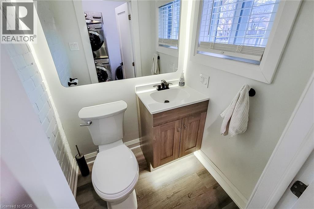 Half bathroom featuring vanity, light wood-style flooring, and stacked washer and dryer - 97 Keith Street, Hamilton, ON - Indoor Photo Showing Bathroom