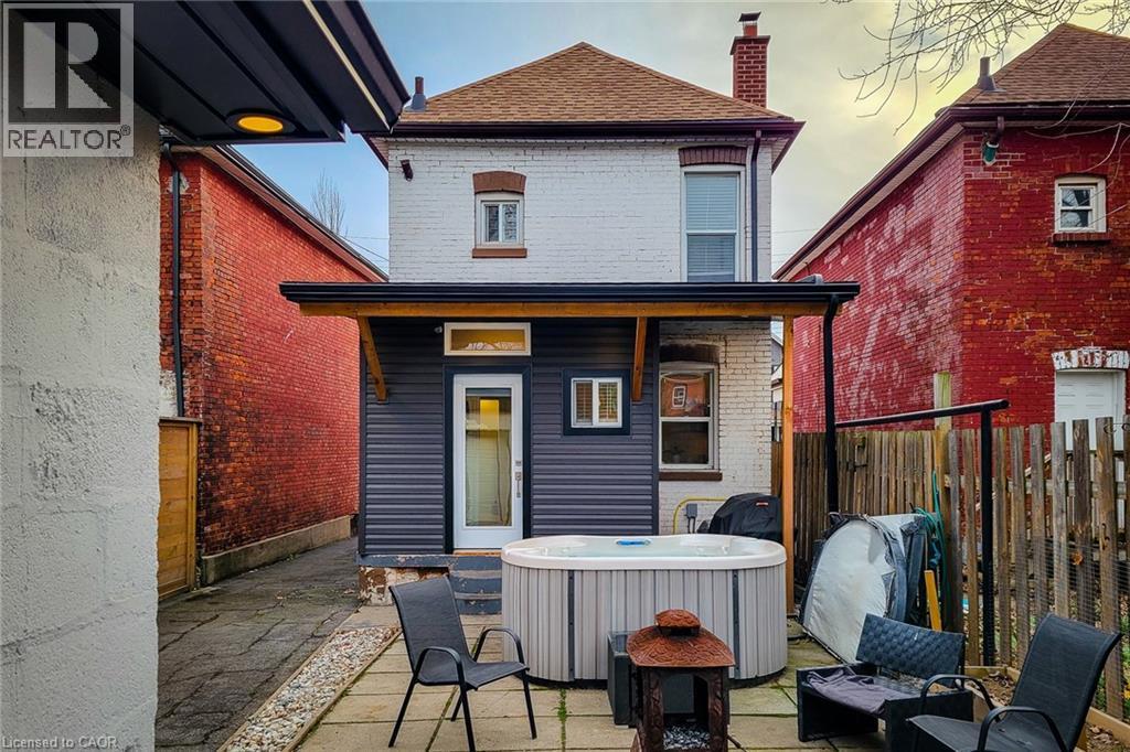 Rear view of property featuring brick siding, a chimney, a hot tub, and roof with shingles - 97 Keith Street, Hamilton, ON - Outdoor
