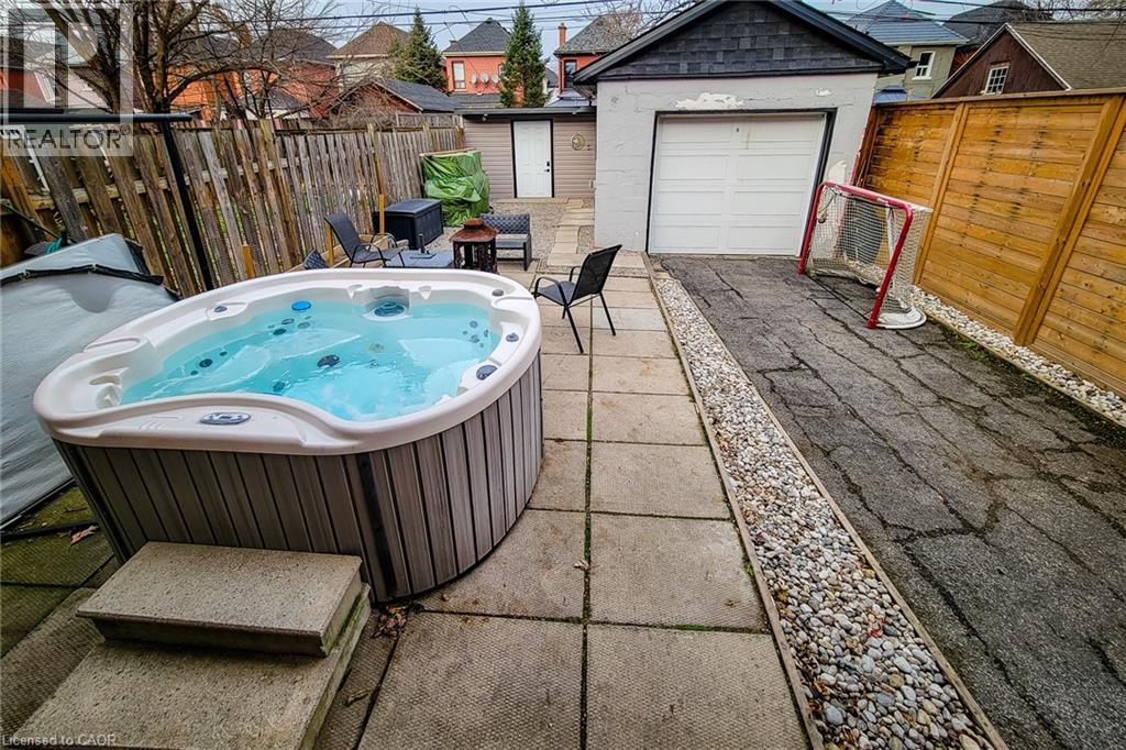 Fenced backyard featuring an outbuilding, a patio area, and a hot tub - 97 Keith Street, Hamilton, ON - Outdoor With Deck Patio Veranda