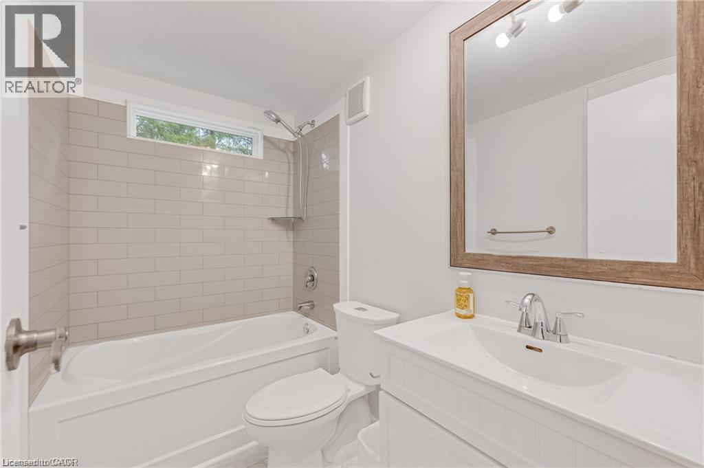 Bathroom featuring a white vanity with integrated sink, chrome faucet, and a large wood-framed mirror - 157 Maple Crescent, Hamilton, ON - Indoor Photo Showing Bathroom