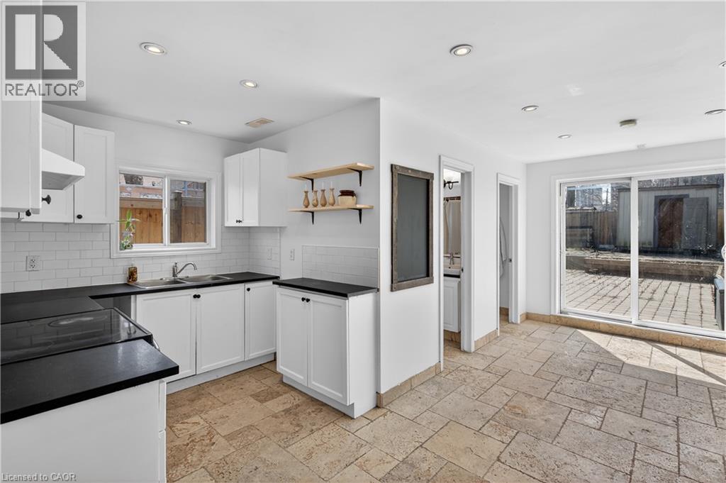 Kitchen featuring dark countertops, white cabinetry, stone tile flooring, open shelves, and exhaust hood - 216 Robert Street, Hamilton, ON - Indoor Photo Showing Kitchen With Double Sink With Upgraded Kitchen