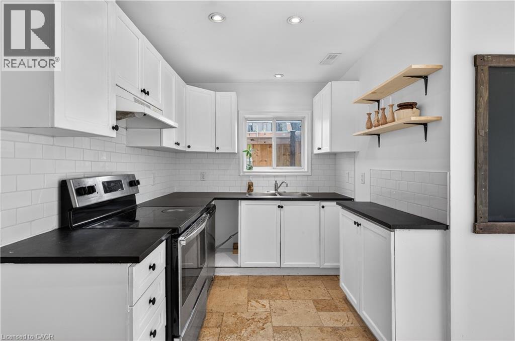 Kitchen with electric range, white cabinets, open shelves, stone tile flooring, and dark countertops - 216 Robert Street, Hamilton, ON - Indoor Photo Showing Kitchen With Double Sink With Upgraded Kitchen