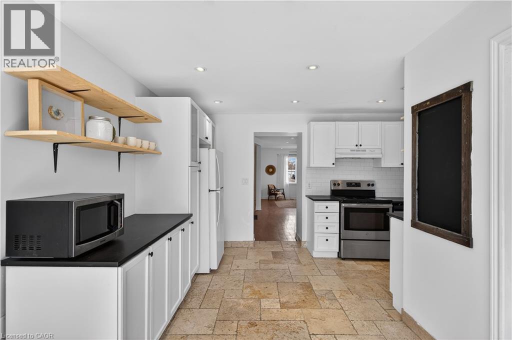 Kitchen featuring dark countertops, white cabinetry, stainless steel appliances, stone tile flooring, and open shelves - 216 Robert Street, Hamilton, ON - Indoor Photo Showing Kitchen